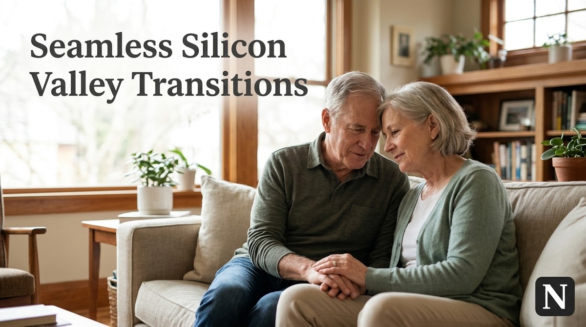 A senior couple sits on a couch, holding hands, with a window and bookshelf in the background.