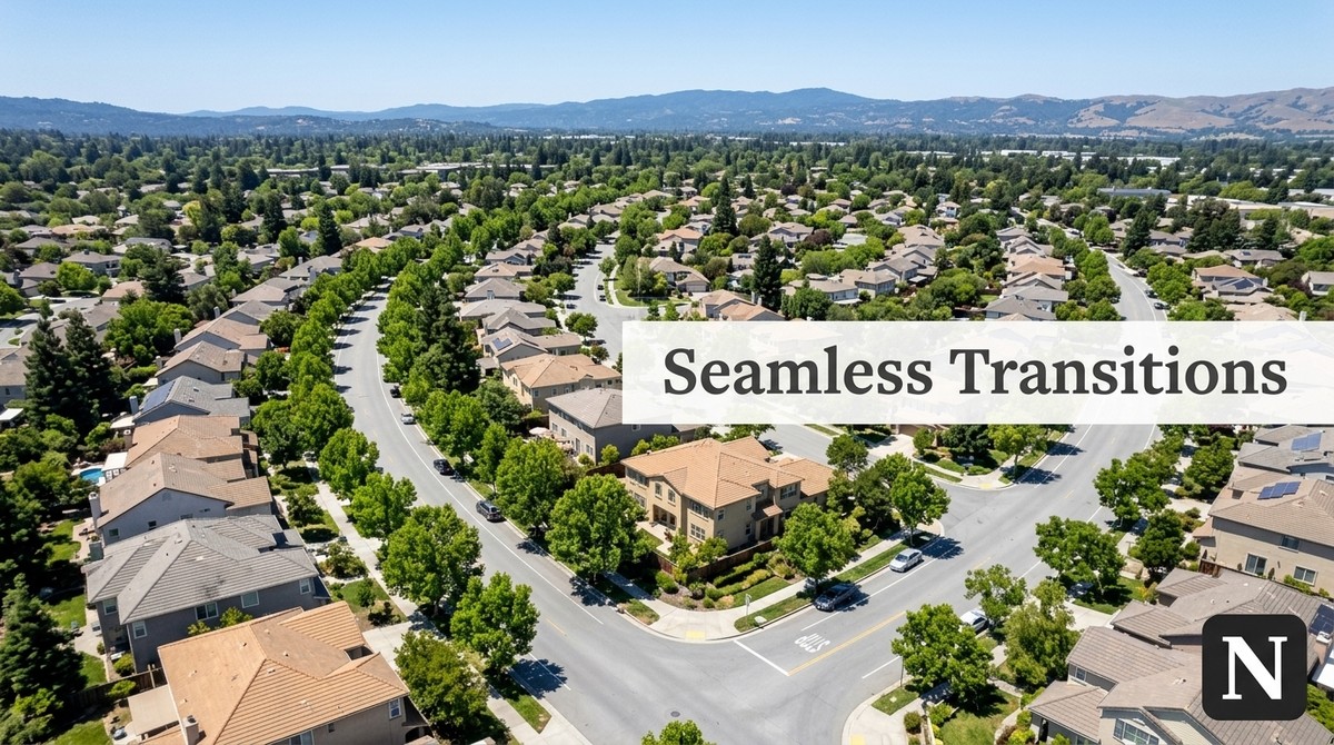 Aerial view of a suburban neighborhood with many houses, green trees, and winding roads. Mountains in distance.