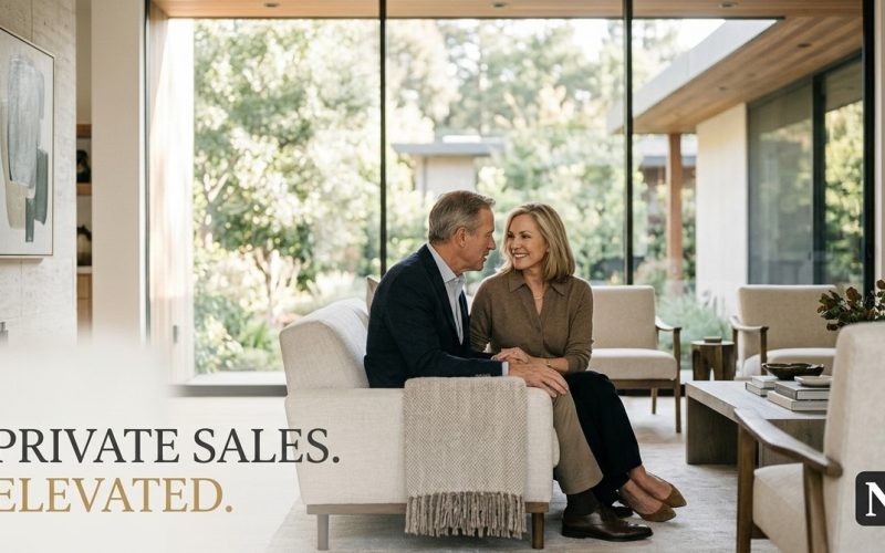 A couple sits on a sofa in a modern living room with large windows overlooking a lush garden.
